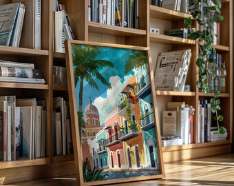 May include: A framed watercolor print depicting a colorful street scene with buildings in shades of pink, turquoise, and yellow. Palm trees and a domed building are also visible. The artwork is displayed on a wooden floor in front of a bookshelf.