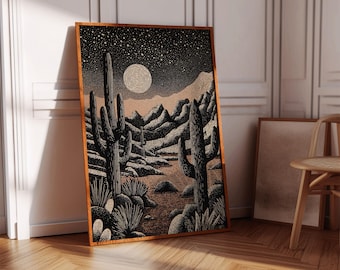 May include: A framed art print depicting a desert landscape at night. The black and white illustration features cacti, mountains, and a starry sky with a textured moon. The artwork is in a wooden frame, leaning against a white wall.