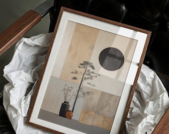 May include: A framed art print with a minimalist design. The artwork features a tree, vase, and a black circle against a neutral background. The print is in a wooden frame with a white mount, resting on white paper in a leather chair.