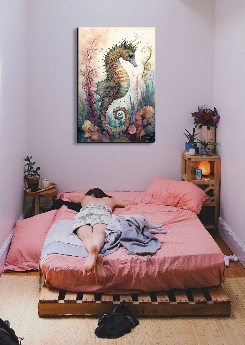 Puede incluir: Una pintura de acuarela de un caballito de mar con una corona de coral y algas marinas. El caballito de mar es azul, verde y marr&oacute;n sobre un fondo amarillo. La pintura est&aacute; enmarcada y colgada en una pared sobre una cama.