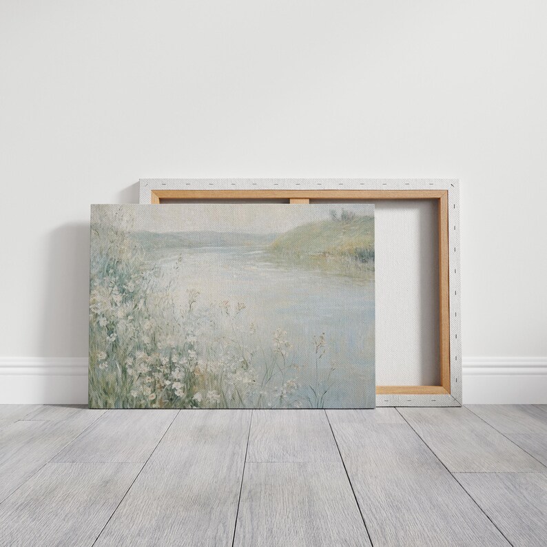 K&ouml;nnte beinhalten: Ein Gem&auml;lde, das eine Flussszene mit einem grasbewachsenen Ufer und wei&szlig;en Blumen im Vordergrund zeigt. Das Wasser ist hellblau und der Himmel ist hellgrau.