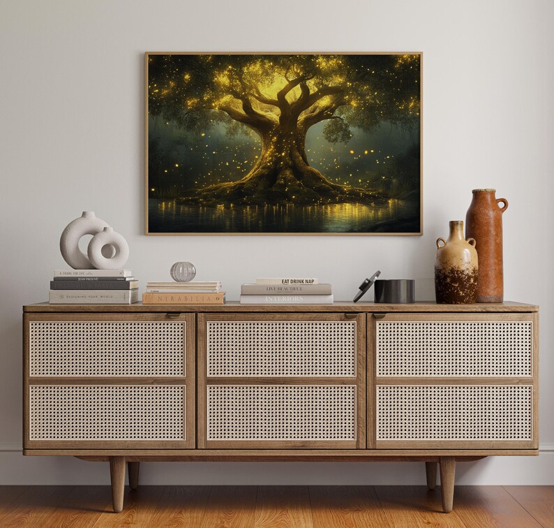 Puede incluir: Una impresi&oacute;n enmarcada muestra un &aacute;rbol luminoso con una copa dorada y luces brillantes, sobre un fondo oscuro. La obra de arte se exhibe sobre un mueble de madera con paneles de puerta tejidos, adornado con jarrones y libros.