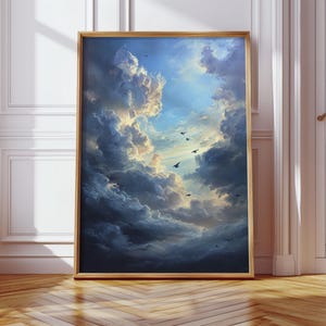 May include: Framed artwork depicting a dramatic sky filled with dark, billowing clouds and patches of bright blue. Several birds are silhouetted against the light. The artwork is in a gold-colored frame and rests on a wooden floor.