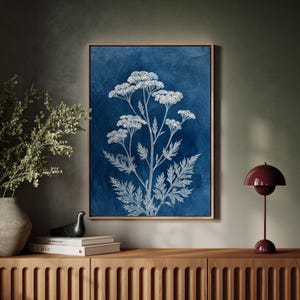 May include: A framed botanical print featuring a white floral illustration against a deep blue background. The artwork is displayed in a wooden frame and is part of a home decor collection. The print showcases detailed plant anatomy.