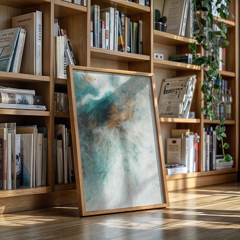 Pu&ograve; includere: Una stampa artistica astratta incorniciata con una cornice in legno. L'opera presenta una miscela di colori verde acqua, bianco e oro, creando un effetto strutturato simile all'acquerello. La stampa &egrave; appoggiata a una libreria in legno piena di libri.