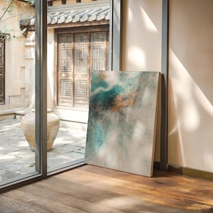 Pu&ograve; includere: Un dipinto astratto con pennellate turchesi, arancioni e bianche &egrave; appoggiato a un muro. L'opera d'arte &egrave; esposta su un pavimento in legno, con vista su un edificio tradizionale attraverso una finestra.