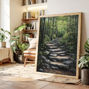 May include: A framed landscape painting depicts a stone staircase winding through a lush forest. The artwork features a palette of greens and browns, with sunlight filtering through the trees. The frame is made of light-colored wood.
