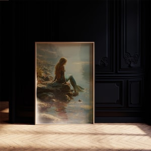 May include: A framed art print depicts a mermaid sitting on a rocky shore, gazing at the water. The mermaid has long, flowing auburn hair and a teal tail. The artwork is in a vintage style, with soft colors and a dreamy atmosphere.