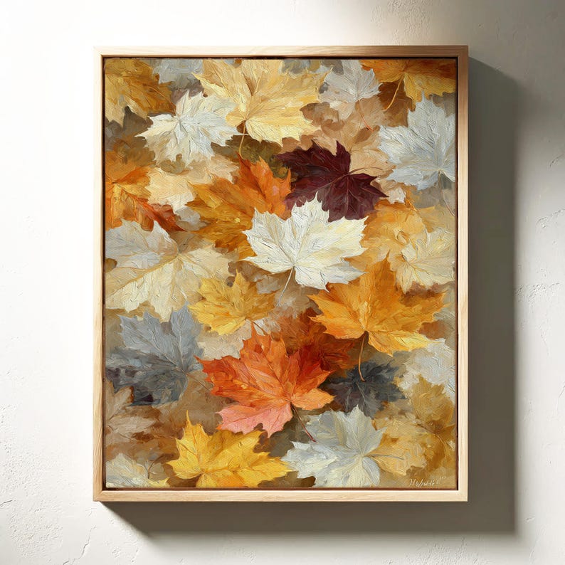 May include: A framed canvas art print depicting a close-up of fallen maple leaves. The leaves are painted in shades of yellow, orange, white, and burgundy. The artwork is set in a light brown wooden frame.