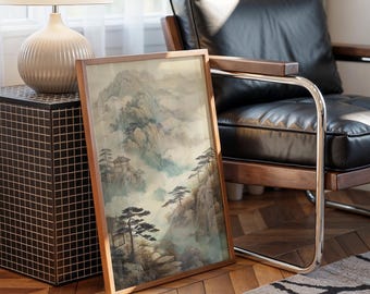 May include: A framed landscape art print featuring a traditional Asian mountain scene with misty valleys, trees, and small buildings. The artwork has a wooden frame and is leaning against a black leather chair and a side table with a lamp.