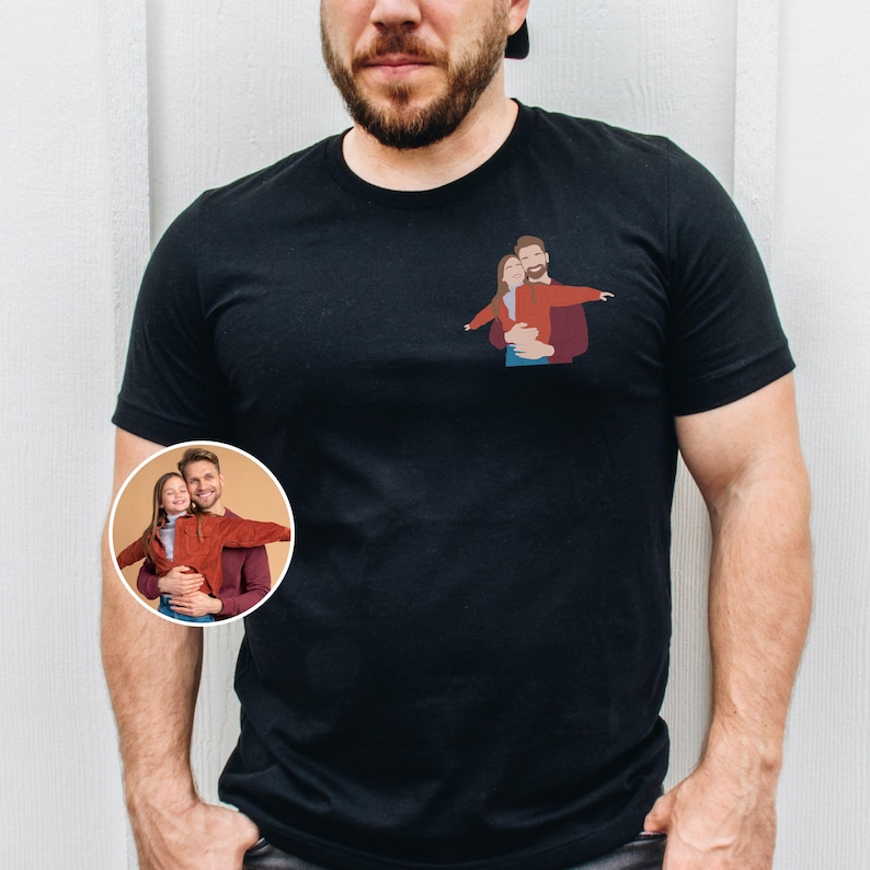 Pu&ograve; includere: T-shirt nero con una piccola illustrazione di una coppia che si abbraccia, con le braccia tese. Un'immagine circolare della stessa coppia si trova in basso a sinistra. La coppia indossa abiti rossi e marroni.