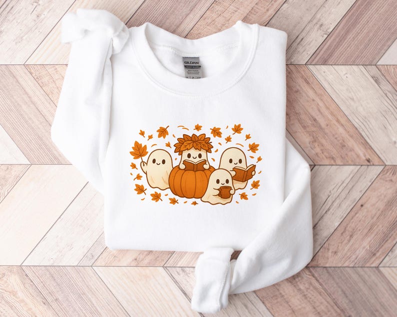 Peut inclure: Sweat-shirt blanc avec un motif sur le th&egrave;me de l'automne. Le motif repr&eacute;sente quatre fant&ocirc;mes de dessins anim&eacute;s, une citrouille et des feuilles d'automne. Un fant&ocirc;me est &agrave; l'int&eacute;rieur de la citrouille, et les autres lisent des livres ou tiennent une tasse.