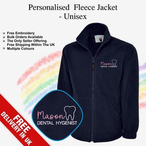 Peut inclure: Veste polaire bleu marine avec fermeture éclair intégrale et col montant. Le texte "Mason DENTAL HYGENIST" est en rose. L'image comprend également un logo avec le même texte et un dessin de dent. Le texte "Personalised Fleece Jacket - Unisex" est en haut.