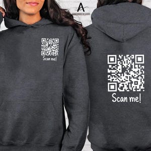 May include: A dark grey hoodie with a white QR code and the text "Scan me!" on the front and back.