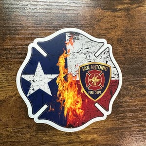 May include: A sticker featuring the Texas state flag and a fire graphic. The sticker has a white border and includes the text "San Antonio Fire Dept." in a shield design.