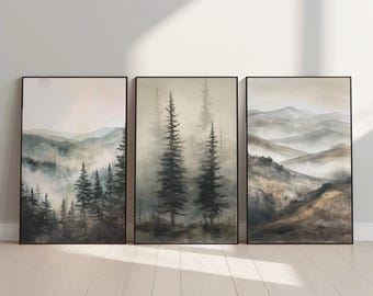 May include: A set of three framed wall art prints featuring landscape scenes. The left print shows misty mountains and pine trees, the center print depicts two tall pine trees in fog, and the right print displays layered mountain ridges in neutral tones.