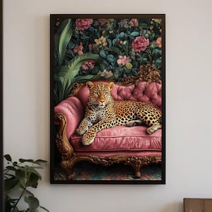 May include: A framed wall art print featuring a leopard resting on a tufted pink velvet sofa. The background displays a lush botanical scene with large green leaves and pink flowers. The sofa has an ornate, carved wooden frame with gold accents.