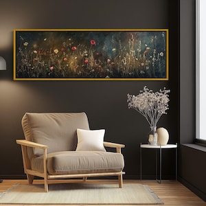 Könnte beinhalten: Gerahmter Kunstdruck auf Leinwand mit floralem Motiv und goldenem Rahmen. Das Kunstwerk zeigt ein Feld mit Wildblumen in Rot-, Weiß- und Gelbtönen vor dunklem Hintergrund. Das Gemälde hängt über einem beigen Sessel mit Holzarmlehnen.