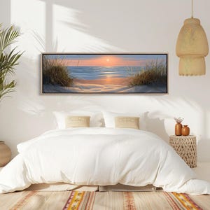 May include: A panoramic rectangular wall art print featuring a serene beach landscape at sunset. The scene depicts calm blue ocean waves meeting a sandy shore with tall dune grasses on both sides, all under a soft orange and pink sky.