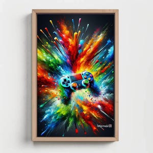 Op de afbeelding: Een ingelijste rechthoekige wandkunstprint met een zwarte videogamecontroller in het midden van een levendige, veelkleurige explosie van verfspatten en strepen in rood, geel, blauw en groen, met de tekst Antarmada in de hoek.