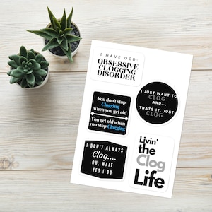 May include: A set of six black and white stickers with humorous sayings about clogging. The stickers feature phrases like "I have OCD: Obsessive Clogging Disorder" and "Livin' the Clog Life".