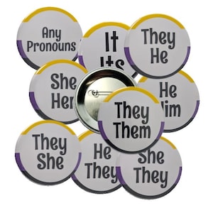 Puede incluir: Un conjunto de botones redondos con pronombres, con bordes amarillos y morados. Los textos en los botones incluyen "Any Pronouns", "It/Its", "They/He", "She/Her", "He/Him", "They/Them", "They/She" y "He/They/She."
