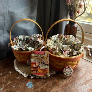May include: Two Longaberger wicker baskets with floral fabric liners. The baskets are yellow and red with a brown wooden handle. A tag is attached to one basket that reads "1998 Mother's Day Basket".