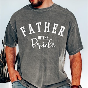 May include: A gray t-shirt with the text "Father of the Bride" in white lettering.