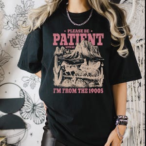 a woman wearing a black t - shirt with the words please to patient i '