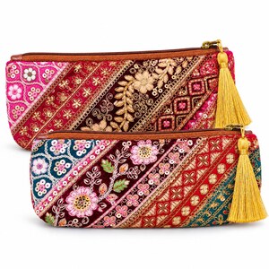Puede incluir: Dos estuches rectangulares con cremallera que presentan intrincados bordados y adornos de lentejuelas en tonos rosa, rojo, verde azulado y dorado. Cada estuche tiene un cierre de cremallera marrón y una borla larga de color amarillo dorado.
