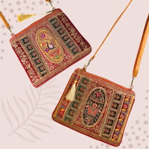 May include: Two embroidered crossbody bags with intricate designs. The bags feature a red and gold color scheme with detailed floral and bird motifs. Each bag has a long, adjustable strap and a decorative tassel.