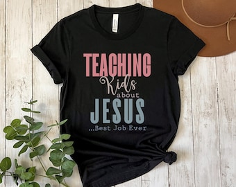 May include: Black t-shirt with the text "TEACHING Kids about JESUS...Best Job Ever" in pink and blue lettering.