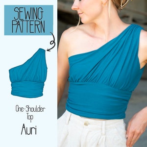 May include: A sewing pattern for a one-shoulder top called "Auri". The pattern shows a teal blue top with a draped neckline and a fitted bodice.