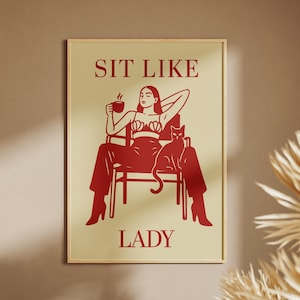 Puede incluir: Lámina artística enmarcada en rojo y beige con el texto "SIT LIKE LADY". La ilustración representa a una mujer en una silla, sosteniendo una taza, con un gato. La obra de arte es un diseño minimalista con estética vintage.