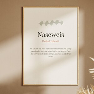 Könnte beinhalten: Ein gerahmtes Wandbild mit hellbeigem Hintergrund und einer kleinen grauen Blattillustration oben. Der Text lautet Naseweis, [Paulina] Substantiv, gefolgt von einer deutschen Definition, die ein Kind beschreibt, das alles weiß.