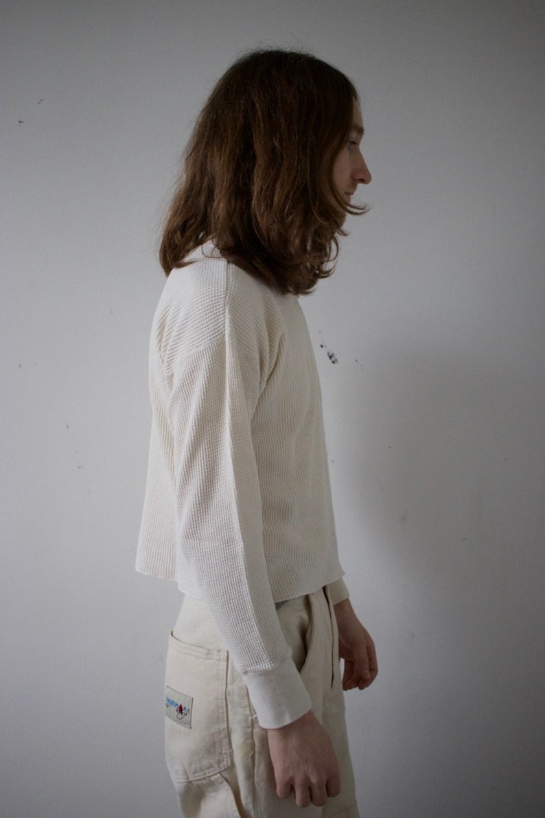 K&ouml;nnte beinhalten: Eine Person tr&auml;gt ein wei&szlig;es, lang&auml;rmliges Waffelpiqu&eacute;-Shirt und eine beige Arbeitshose.