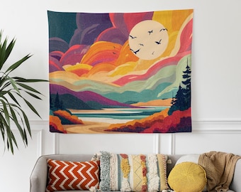 May include: A colorful tapestry depicting a landscape scene with a large sun, birds, and layered mountains. The artwork features shades of orange, yellow, purple, and blue. The tapestry is hanging on a white wall above a gray sofa with decorative pillows.