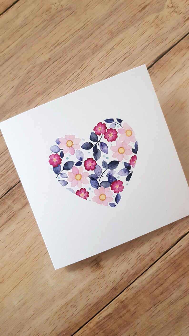 May include: A white card with a pink, purple, and blue floral heart design.