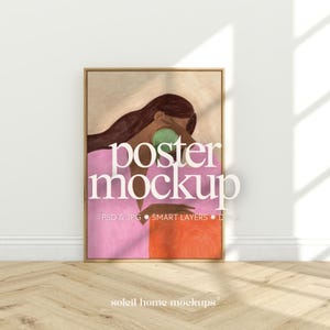 Peut inclure: Une affiche rectangulaire verticale dans un cadre en bois clair présentant l'illustration d'une personne aux longs cheveux bruns vêtue d'un vêtement rose, tenant un objet vert près du visage, avec le texte poster mockup PSD & JPG.