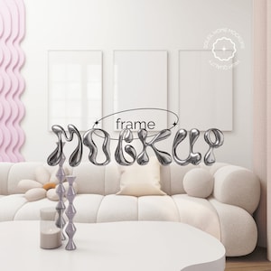 Peut inclure: Un canapé blanc avec un coussin blanc et une table basse blanche devant. Deux cadres photo blancs sont accrochés au mur derrière le canapé. Le mot "frame" est écrit en noir au-dessus du canapé. Le mot "mockup" est écrit en argent dans une police de caractères stylisée.