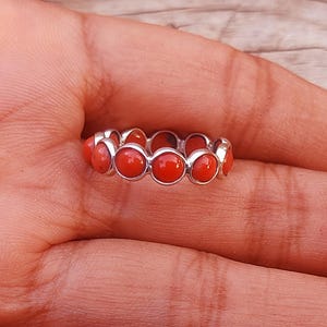 May include: A silver ring with a band of round, red coral stones.