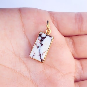 May include: A gold-toned pendant featuring a rectangular white and brown marbled stone.