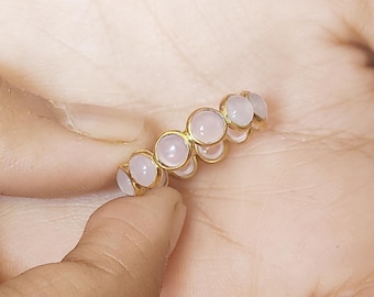 May include: A gold ring with a row of pale pink round stones.