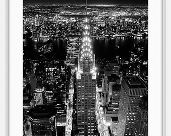 Peut inclure: Une photographie aérienne en noir et blanc du Chrysler Building à New York la nuit. Le bâtiment est éclairé et les lumières de la ville sont visibles en arrière-plan.