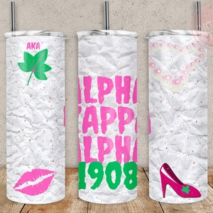 May include: Three white tumblers with a pink and green design. The tumblers have a crumpled paper texture. The designs include a green leaf, the letters "AKA", a pink lip, the letters "ALPHA KAPPA ALPHA" and the number "1908", a string of pearls, and a pink high heel shoe with a green leaf.