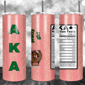 May include: A pink tumbler with a green glitter design and the letters AKA. The tumbler has a black and brown hand with a 1908 charm on the wrist. The tumbler also has a nutrition facts label with the text "AKA Nutrition Facts" and "1 Pretty Girl".