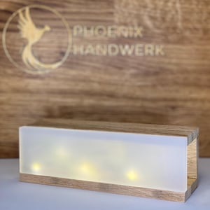 Könnte beinhalten: Eine Holzkiste mit einer mattierten Glasscheibe und warmweißen LED-Lichtern im Inneren. Die Kiste ist mit "PHOENIX HANDWERK" beschriftet.