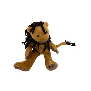 May include: A plush lion toy in shades of brown. The lion has a tan body, dark brown mane, and a tail with a tuft of dark brown fur. The toy is designed with a friendly expression and is made of soft material.