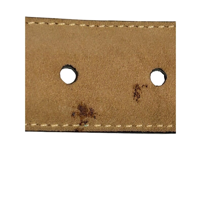 Puede incluir: Primer plano de una secci&oacute;n de un cintur&oacute;n de cuero marr&oacute;n. Se ven dos agujeros circulares, junto con costuras blancas y una mancha oscura. La textura del cintur&oacute;n parece ligeramente desgastada.