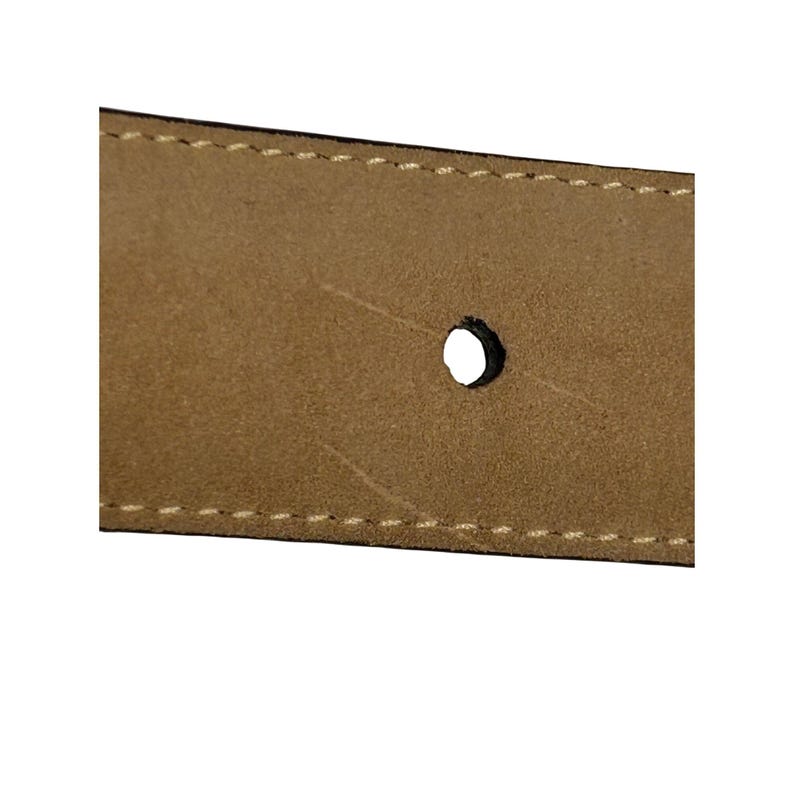 Puede incluir: Primer plano de una secci&oacute;n de un cintur&oacute;n de cuero marr&oacute;n. El cintur&oacute;n tiene un solo agujero y est&aacute; cosido con un hilo de color claro a lo largo de los bordes. El cuero tiene un aspecto ligeramente texturizado.